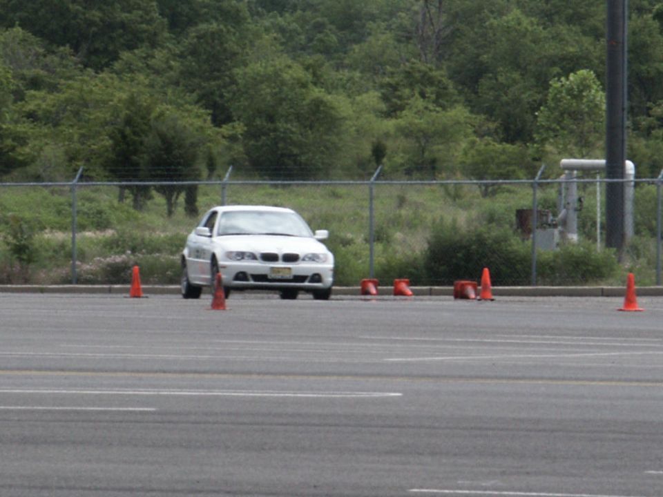 White sedan with a license plate and orange cones on a paved lot