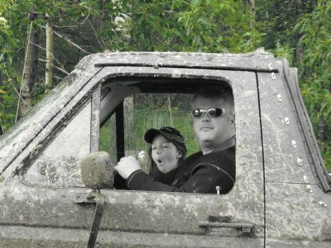 1995 Ford Bronco - Man and child inside a muddy off-road vehicle, possibly during an off-road event.