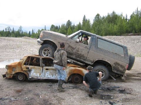 1995 Ford Bronco - A 1995 Ford Bronco is positioned on top of a heavily damaged and burnt car.