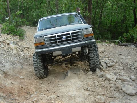 1995 Ford Bronco - This modified Ford F-Series truck navigates a challenging off-road trail with large tires and a snorkel.