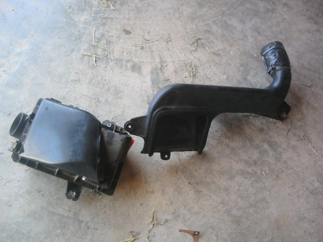 Black plastic air box and intake duct on concrete floor