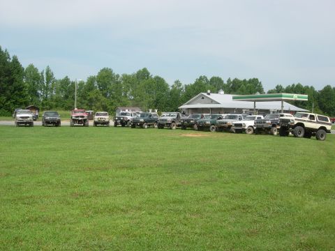 1995 Ford Bronco - A group of SUVs and trucks are parked in a field on a sunny day.