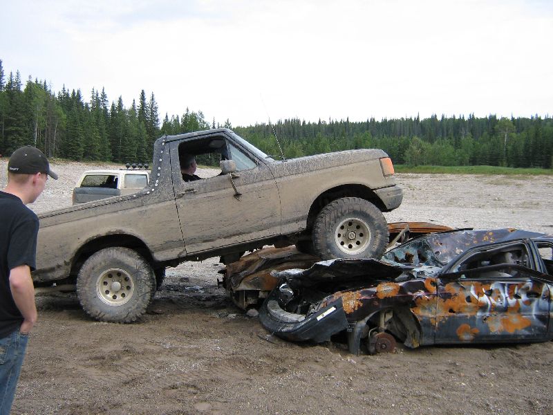 Mud-covered 1995 Ford Bronco on wrecked cars