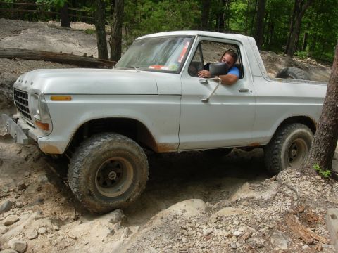 1995 Ford Bronco - White 1978 Ford Bronco tackles a challenging off-road trail with a driver behind the wheel.