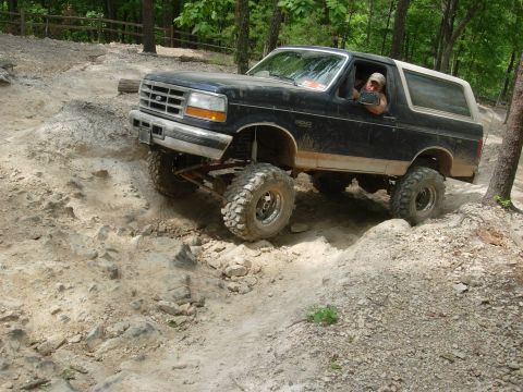 1995 Ford Bronco - Modified 1995 Ford Bronco navigates a challenging off-road course with large tires.