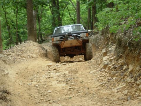 1995 Ford Bronco - A white Ford Bronco navigates a rocky, wooded off-road trail.