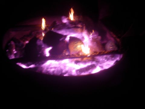 1995 Ford Bronco - A fire pit glows with purple and orange flames and embers, suggesting a nighttime scene.