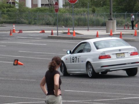 2001 Mercury Grand Marquis - A white BMW coupe navigates a course marked by orange traffic cones, with a woman observing from the side.