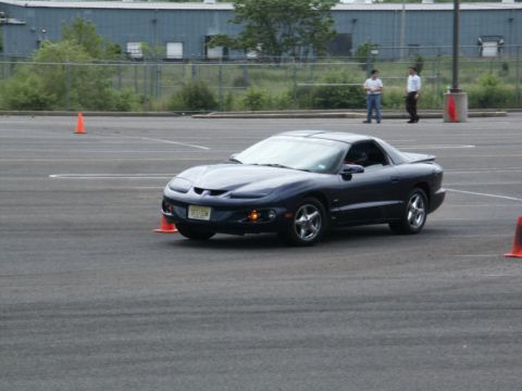 2001 Mercury Grand Marquis - A dark blue Pontiac Firebird navigates an autocross course marked by orange cones.