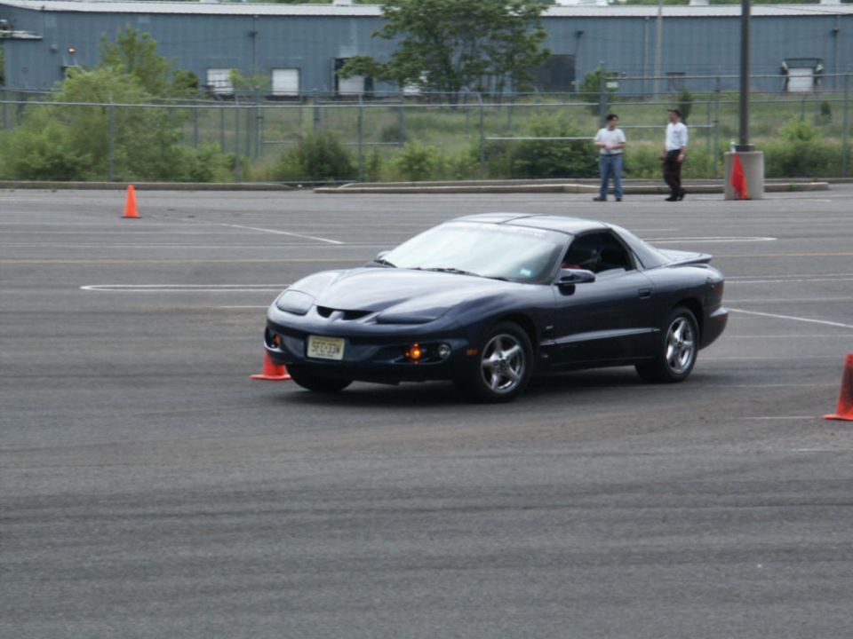 Dark blue Pontiac Firebird on asphalt course with orange cones