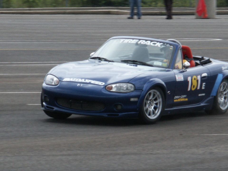 Blue Mazda Miata with 'Mazdaspeed' on hood, 'The Tire Rack' on windshield banner, and race number '181E' on door