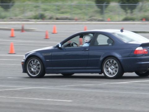 2001 Mercury Grand Marquis - A blue BMW M3 coupe navigates a course marked by orange cones, with a driver wearing a helmet.