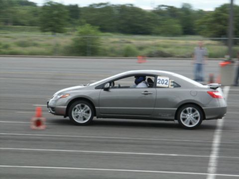 2001 Mercury Grand Marquis - A gray coupe, likely a Honda Civic, navigates a race track with a driver wearing a helmet.