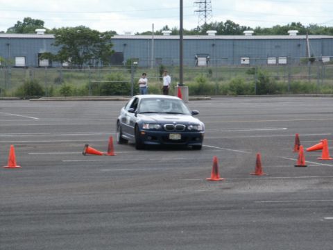 2001 Mercury Grand Marquis - A blue BMW M3 navigates a course marked by orange traffic cones in an open paved area.