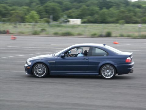 2001 Mercury Grand Marquis - A blue coupe is driven by a person wearing a helmet on a track, with the SUPERMOTORS.NET logo in the lower right corner.