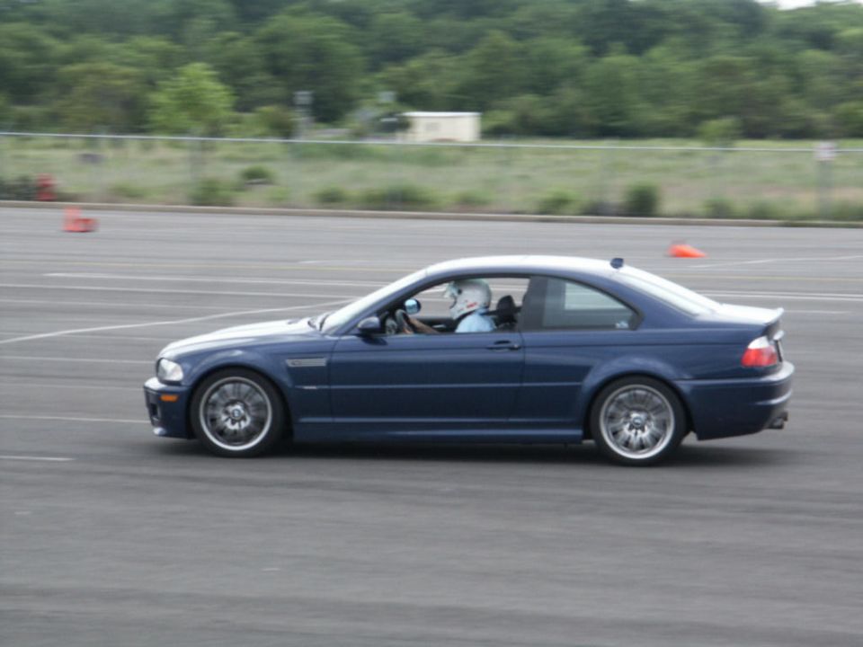 Blue coupe with racing driver on track. SUPERMOTORS.NET logo visible