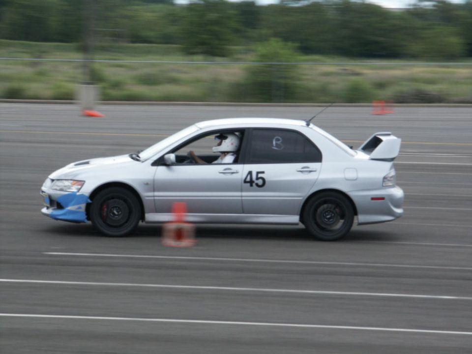 Silver sedan with racing number 45 and a large rear spoiler, on a track