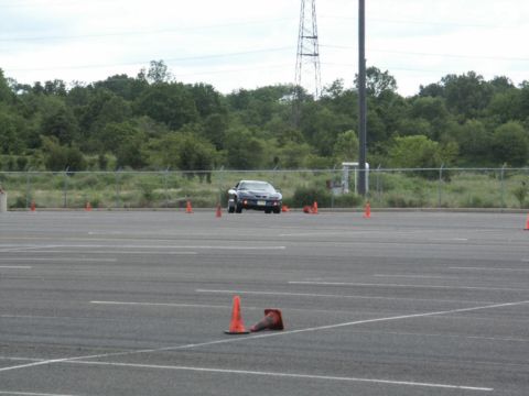 2001 Mercury Grand Marquis - A dark sports car is seen from the front, driving through a course marked by orange traffic cones on a paved lot.