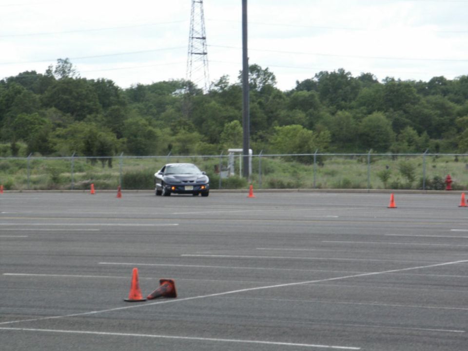 Dark Pontiac Firebird driving through a cone course