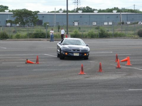2001 Mercury Grand Marquis - A Pontiac Firebird navigates a cone course in an empty parking lot.