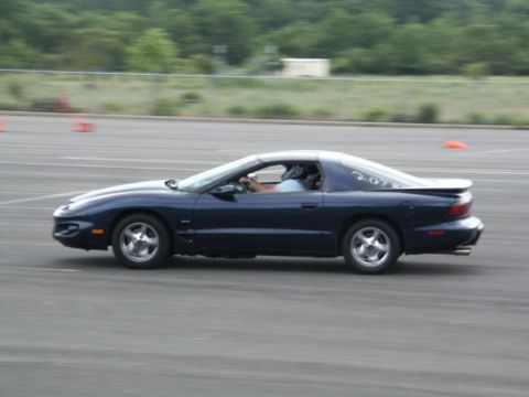 2001 Mercury Grand Marquis - A dark blue coupe, possibly a Pontiac Firebird, navigates a course with orange cones visible in the background.