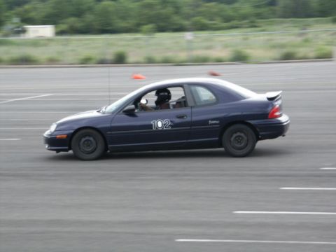 2001 Mercury Grand Marquis - A dark blue coupe with the number 102 on its door navigates a track, with a driver wearing a helmet visible inside.