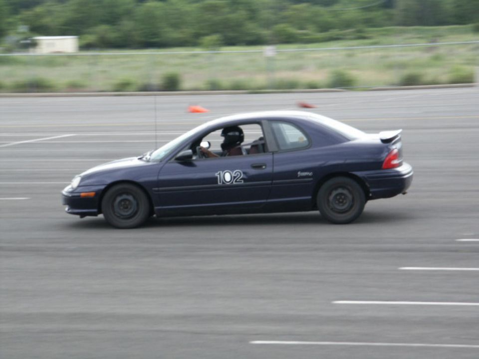 Dark blue coupe with number 102 on the door driving on a track