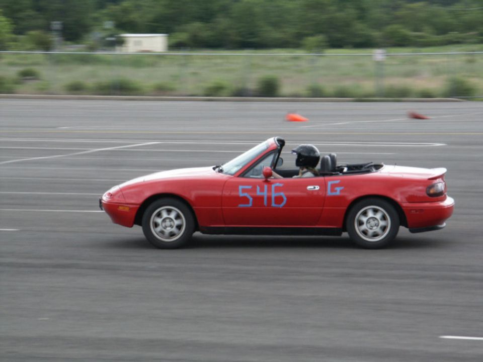 Red convertible sports car with blue numbers 546 and G on the side, driver wearing a helmet
