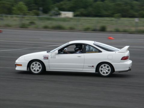 2001 Mercury Grand Marquis - A white coupe with racing decals and a spoiler is seen on a track during a race event.