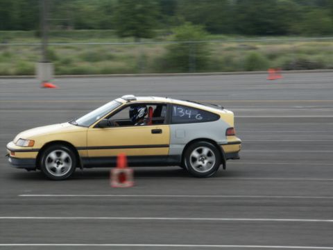 2001 Mercury Grand Marquis - A two-tone Honda CRX with a driver in a helmet navigates a race track with orange cones visible.
