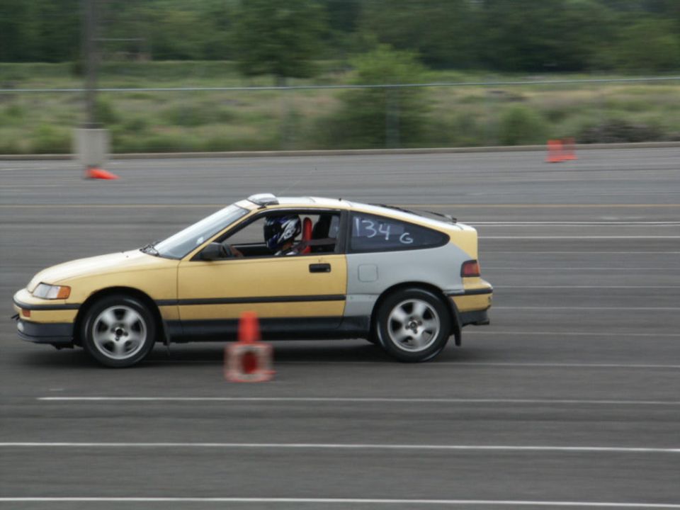 Yellow and silver Honda CRX with racing number 134 G on the rear window, seen from the side on a track