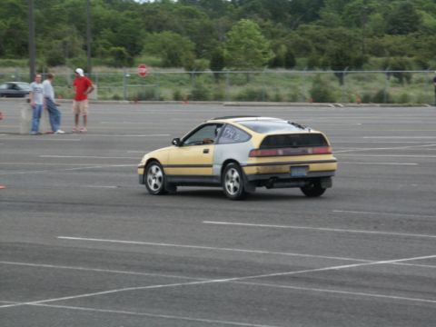 2001 Mercury Grand Marquis - A yellow and grey Honda CRX is seen from the rear in a parking lot, with racing numbers visible on its side.