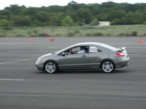 2001 Mercury Grand Marquis - Gray 2006 Honda Civic Si coupe with racing number 202 on the door, driving on a track.