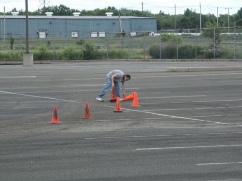 2001 Mercury Grand Marquis - A person is setting up traffic cones in a large, empty parking lot.
