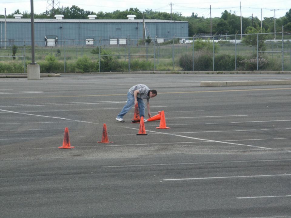 Person arranging orange traffic cones in an empty asphalt parking lot