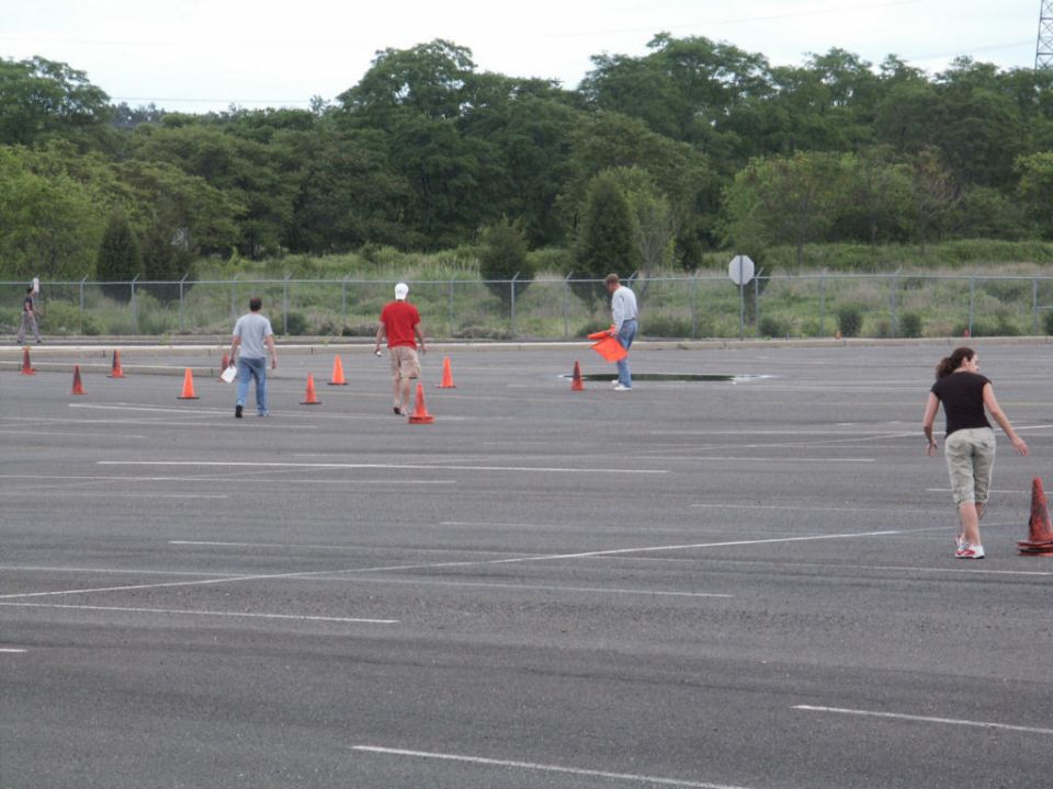 People are setting up cones in a large, empty parking lot