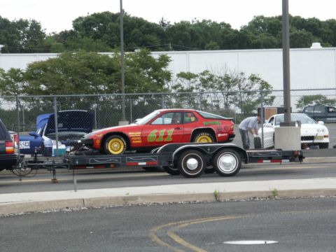2001 Mercury Grand Marquis - A red race car with racing decals is loaded onto a trailer, with a person attending to it.