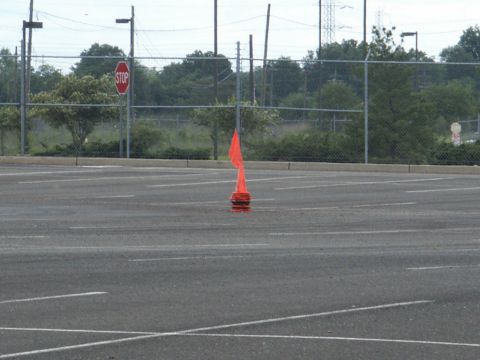 2001 Mercury Grand Marquis - An orange traffic cone stands alone in a vast, empty parking lot under an overcast sky.