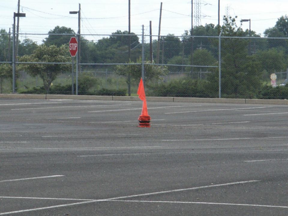 Orange traffic cone with a tattered flag in an empty parking lot