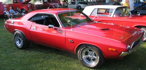 1994 Ford Bronco - A red 1970 Dodge Challenger is parked on grass at an outdoor car show.