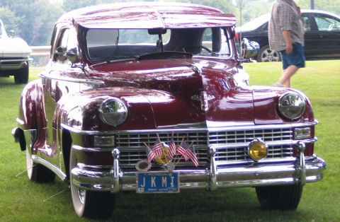 1994 Ford Bronco - A classic car with American flags displayed on its grille sits on a grassy field.