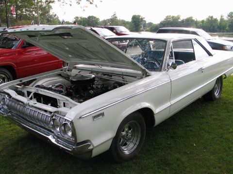 1994 Ford Bronco - A white 1964 Dodge Polara coupe is displayed with its hood open at a car show.