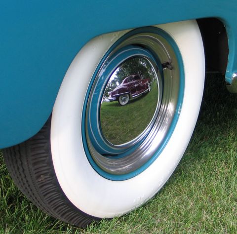 1994 Ford Bronco - A reflection of a classic car is visible in the hubcap of a vehicle with a white-walled tire.
