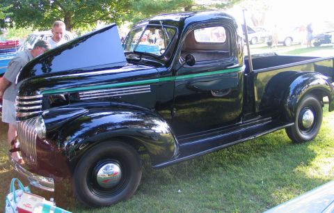 1994 Ford Bronco - A vintage black pickup truck with its hood open is displayed on a grassy field at an outdoor event.