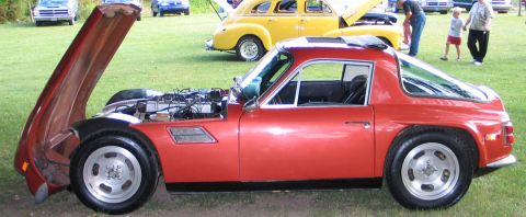 1994 Ford Bronco - A red sports car is displayed with its hood open, revealing the engine compartment at an outdoor car show.