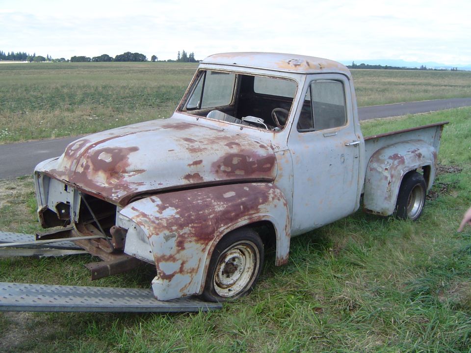 Rusty 1953 Ford F-100 pickup truck on a trailer, front end missing