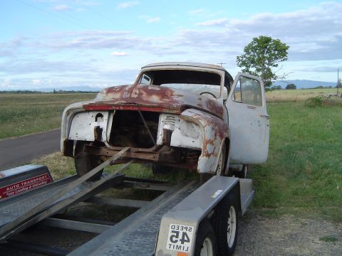 1955 Ford F-100 - This weathered pickup truck, likely from the early 1950s, is being transported on a trailer.