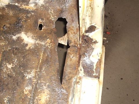 1979 Ford F-150 - The floor pan of a vehicle shows significant rust damage and a large hole, indicating extensive corrosion.
