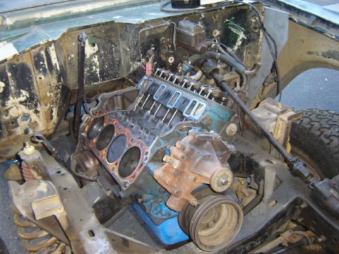 1971 Ford Bronco - Engine bay of a vehicle undergoing a tear-down, revealing a V8 engine with cylinder heads removed. The Supermotors.net logo is visible in t…