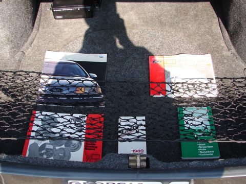 1992 Ford Taurus - The trunk of a car contains several manuals, including one for a 1989 Taurus, and a photograph of a car.